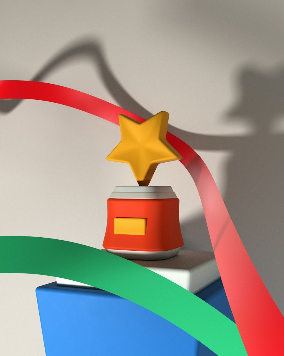 A yellow star trophy on a red base with red and green ribbons